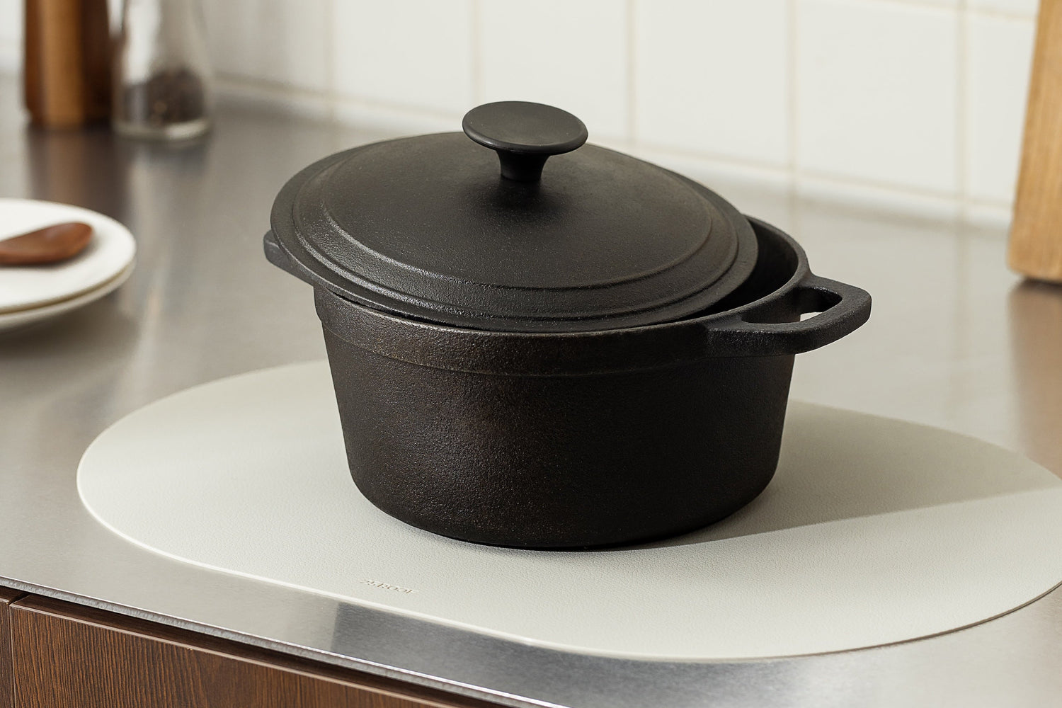 Heat resistant silicone placemat protecting kitchen counter under heavy cast iron pot in modern kitchen