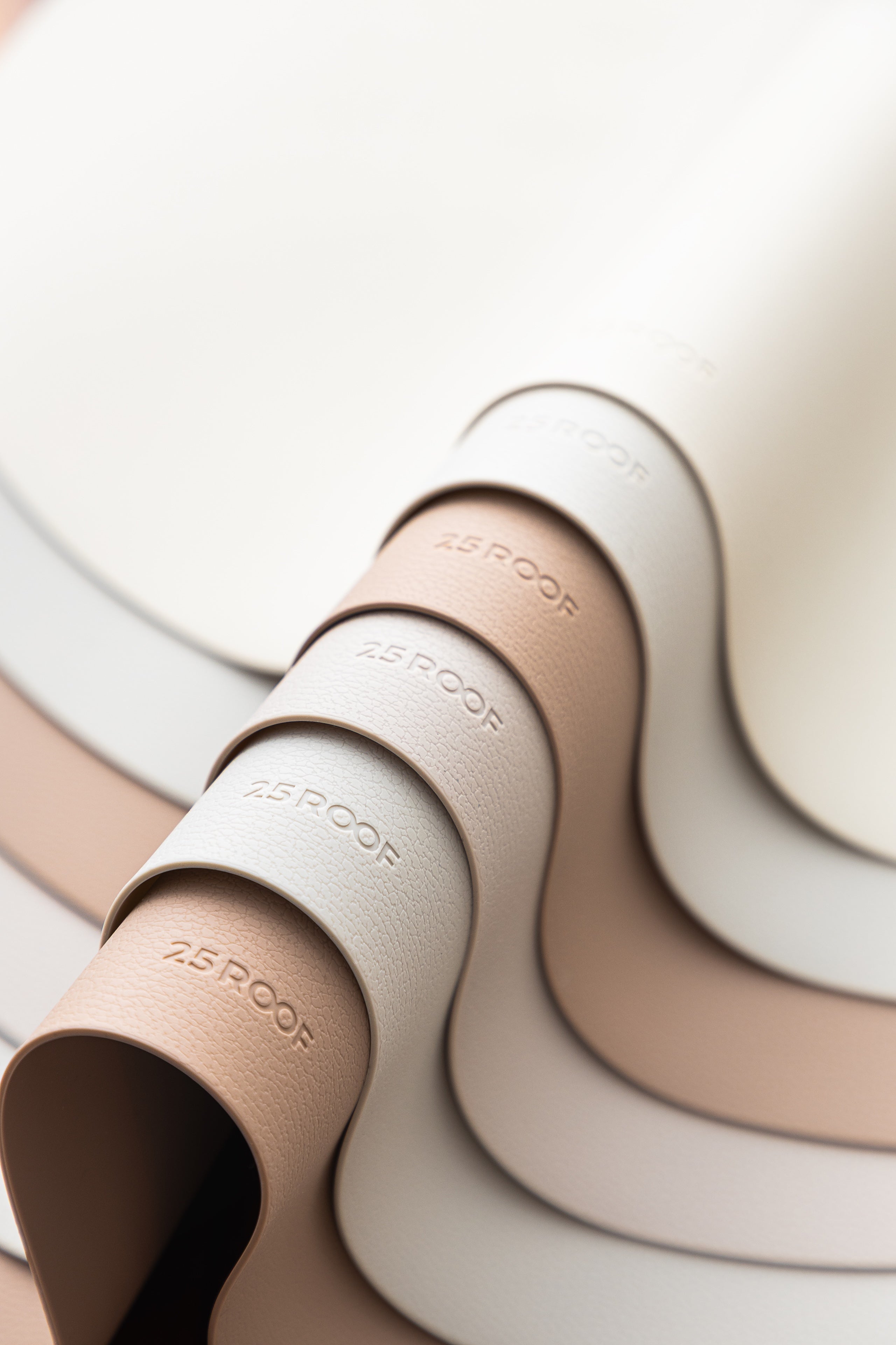 Minimalist silicone placemat set in neutral colors showing flexible rolled design in beige and sandy tones
